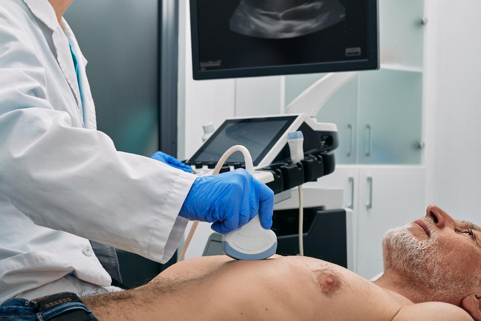 Cardiac sonographer scanning an adult patient’s chest during an echocardiogram