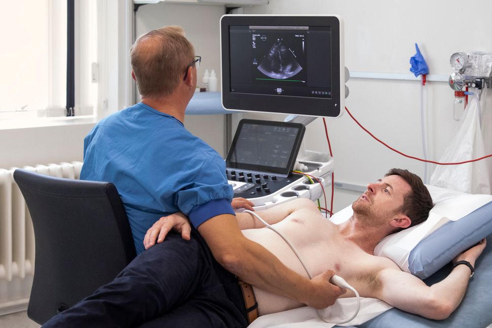 Cardiac sonographer performing an echocardiogram, with the heart visible on the ultrasound screen